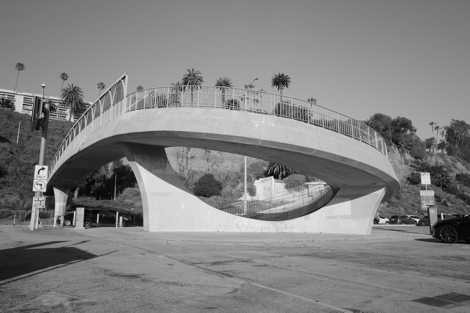 A concrete pedestrian bridge curves around an eye-shaped opening.