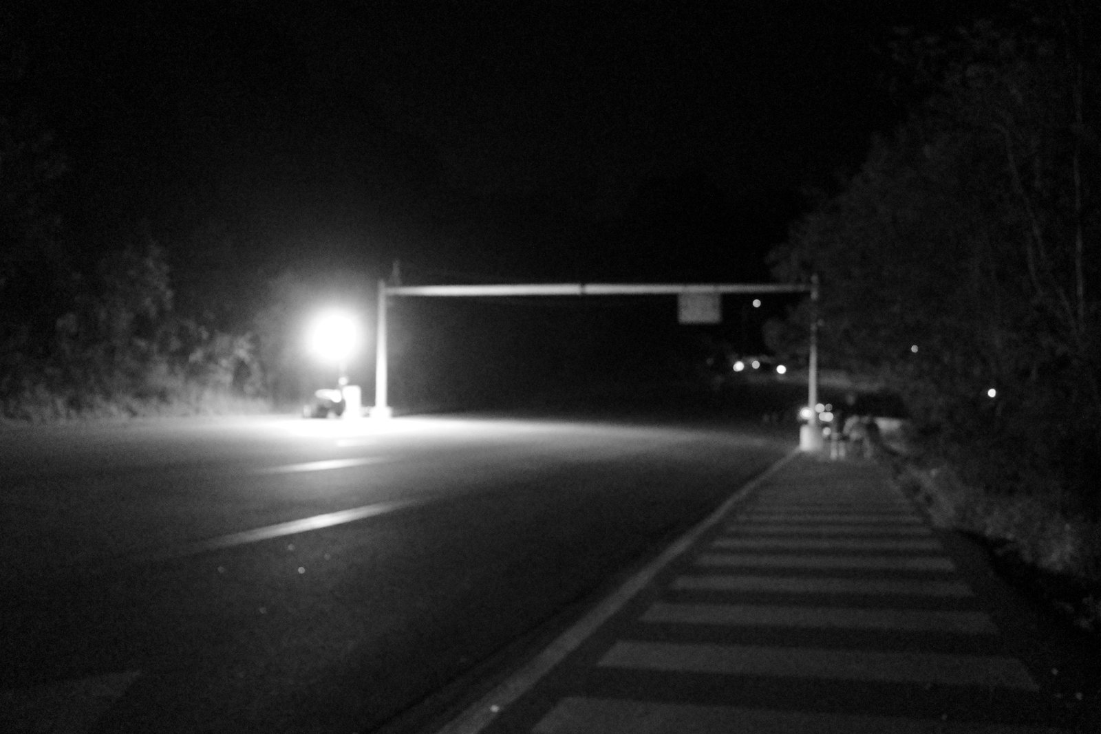 An isolated lamp lights an empty intersection at night.