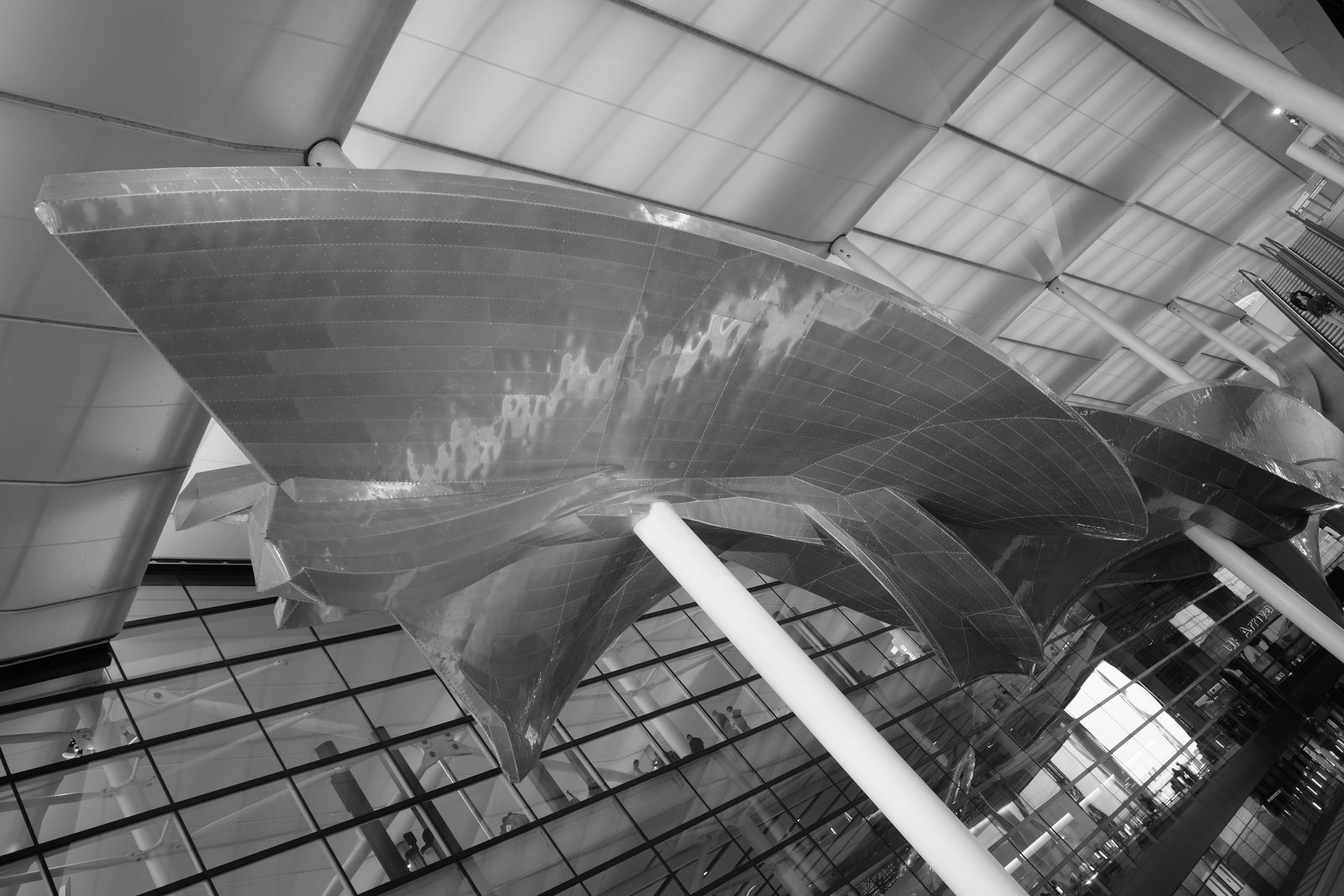 Folded metal ceiling panels meet white struts beneath an airport roof.