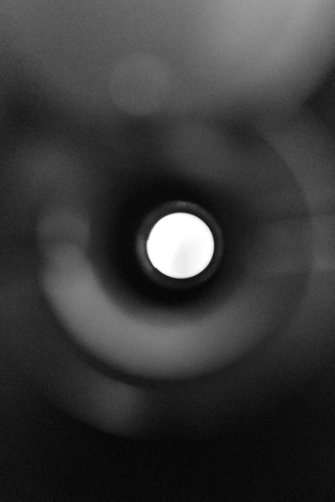 Light shines through a peephole surrounded by soft dark rings.