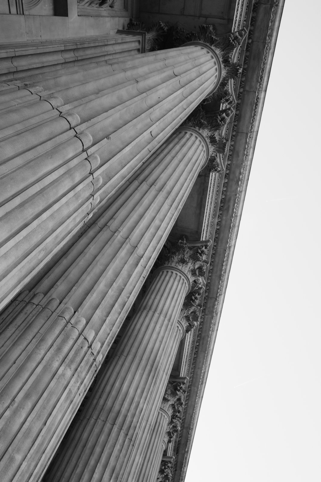 Fluted stone columns rise diagonally beside a narrow strip of sky.