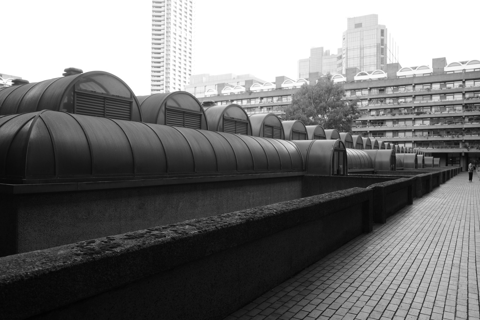 Barrel-shaped roofs repeat beside a textured parapet and tiled walkway.