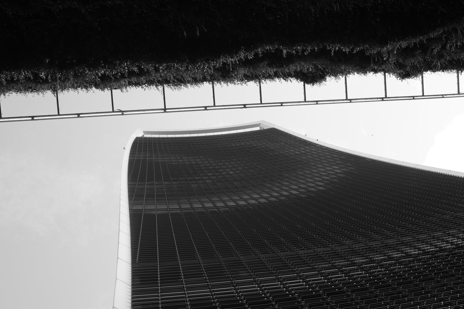 A curved glass tower rises beneath a dark overhead edge.