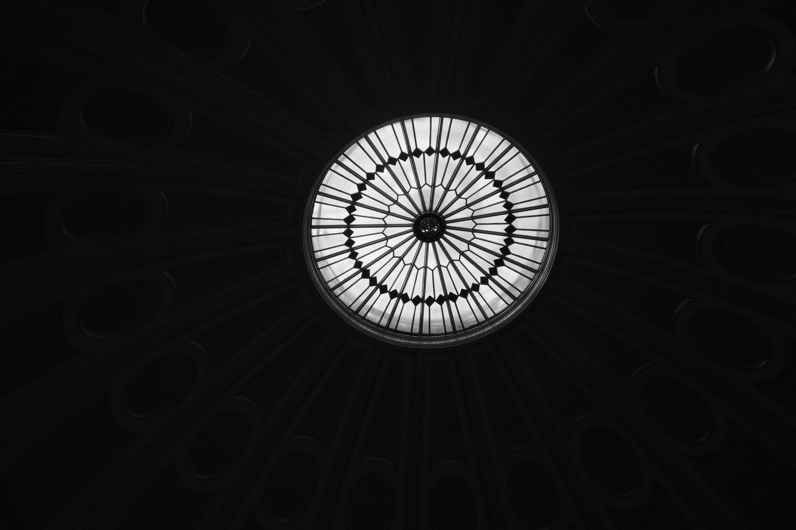 A circular roof light shines within a dark ceiling.