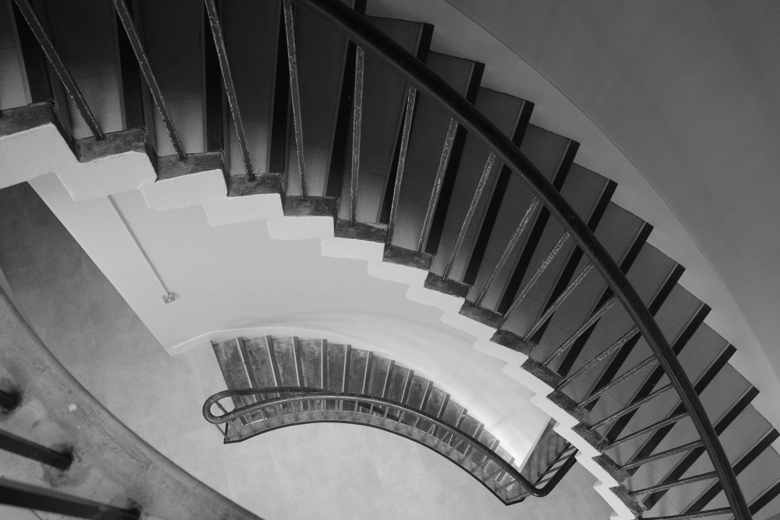 A stair and handrail curve downward in a fan of dark treads.
