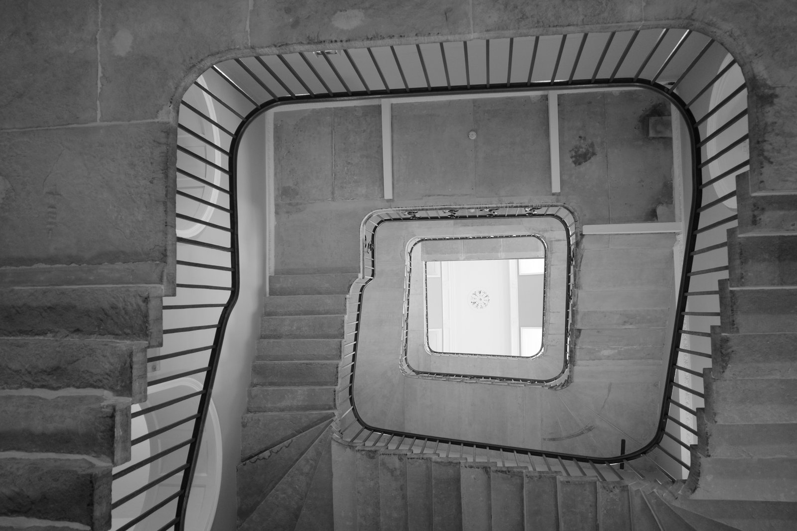 A square stone stairwell recedes toward a bright overhead opening.