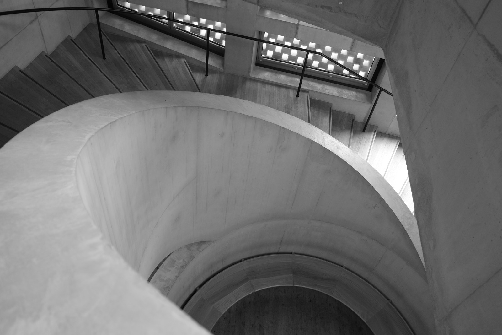 A concrete spiral stair descends around a deep central opening.