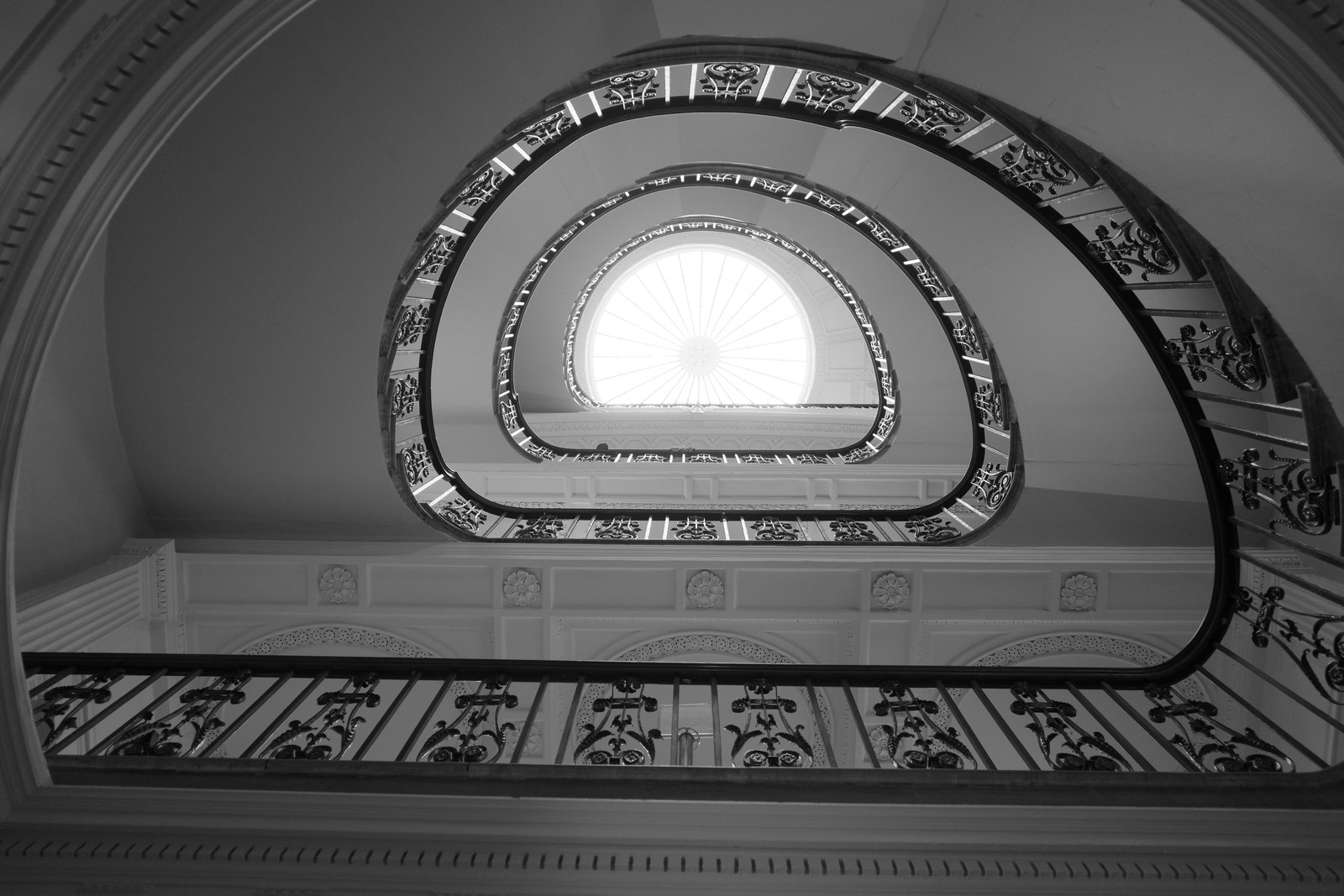 Nested rounded triangular stair openings surround a bright center.