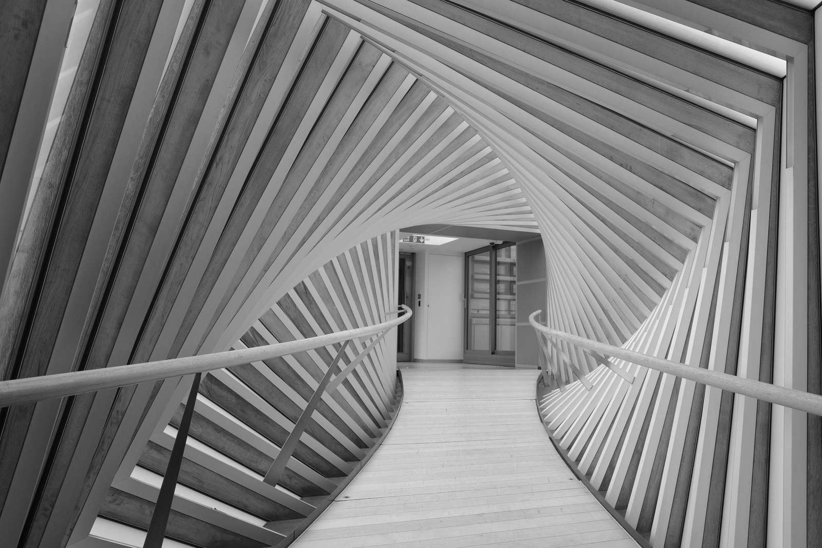 Angled slats twist around a curving enclosed footbridge.