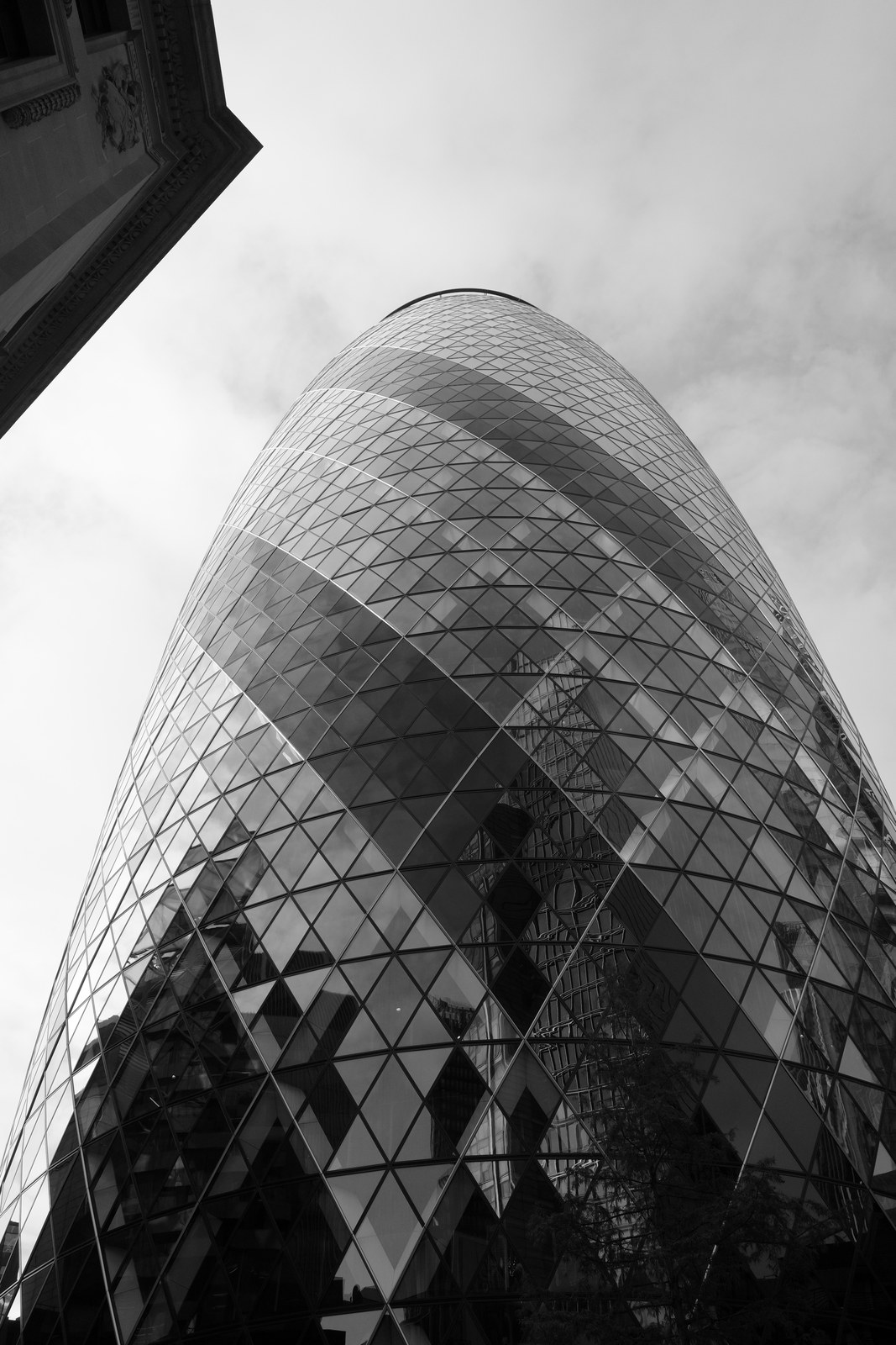 The Gherkin's faceted glass surface curves into a pale sky.
