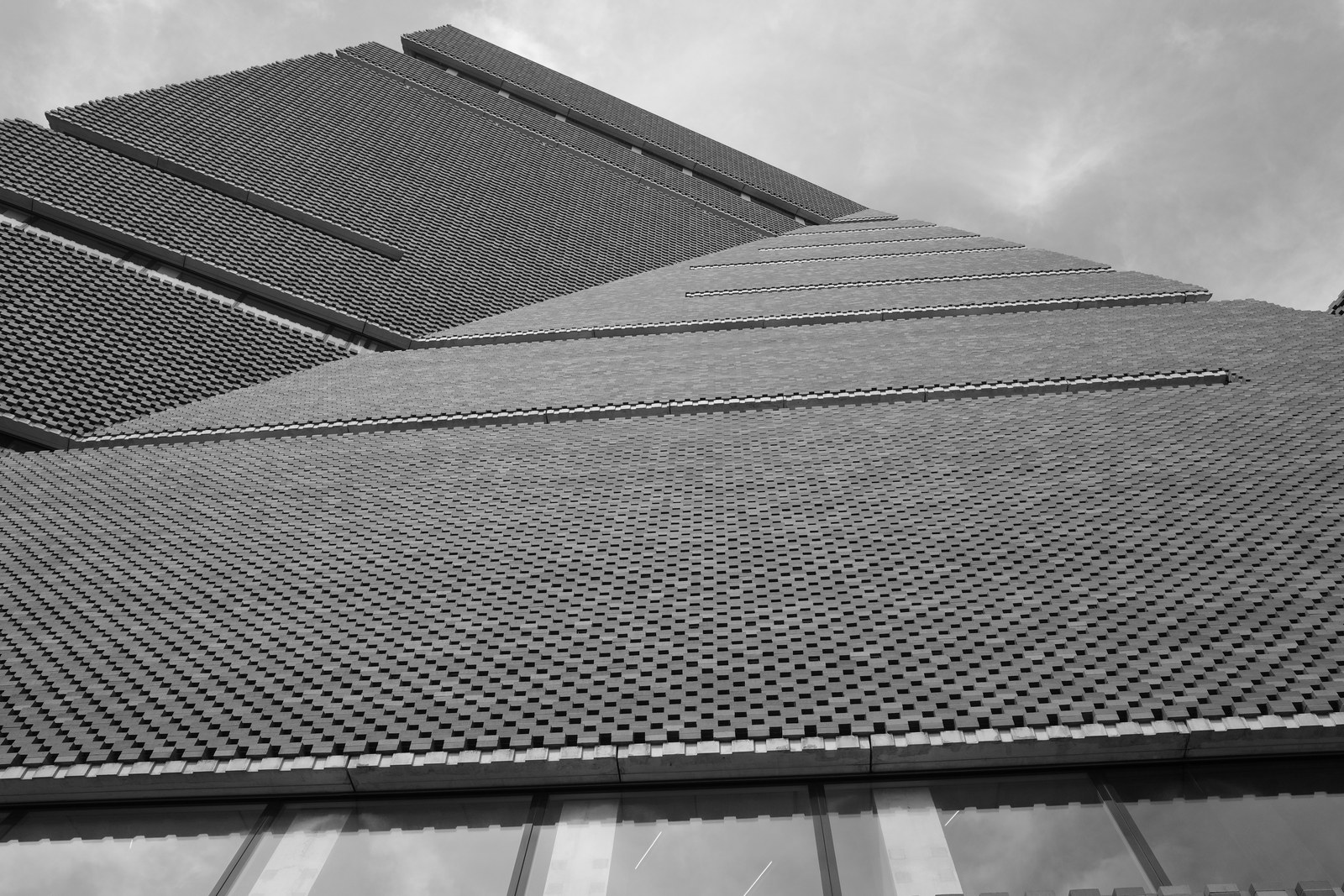 Faceted brick walls rise toward clouded sky.