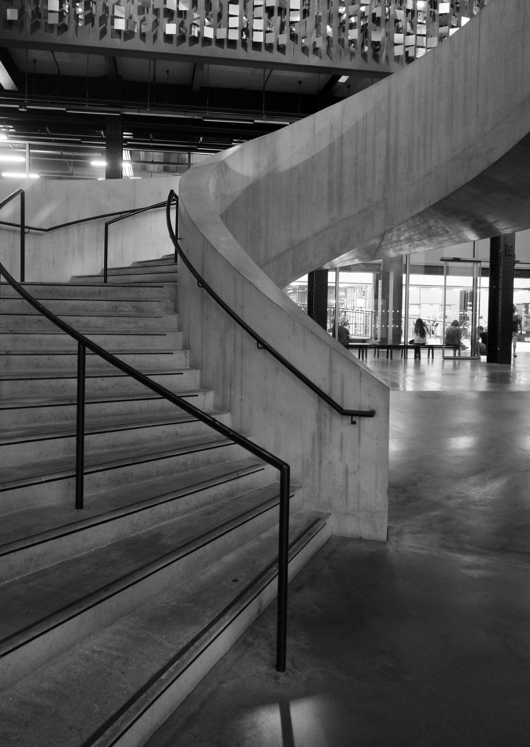 A curved stair and slender handrails rise above a reflective floor.