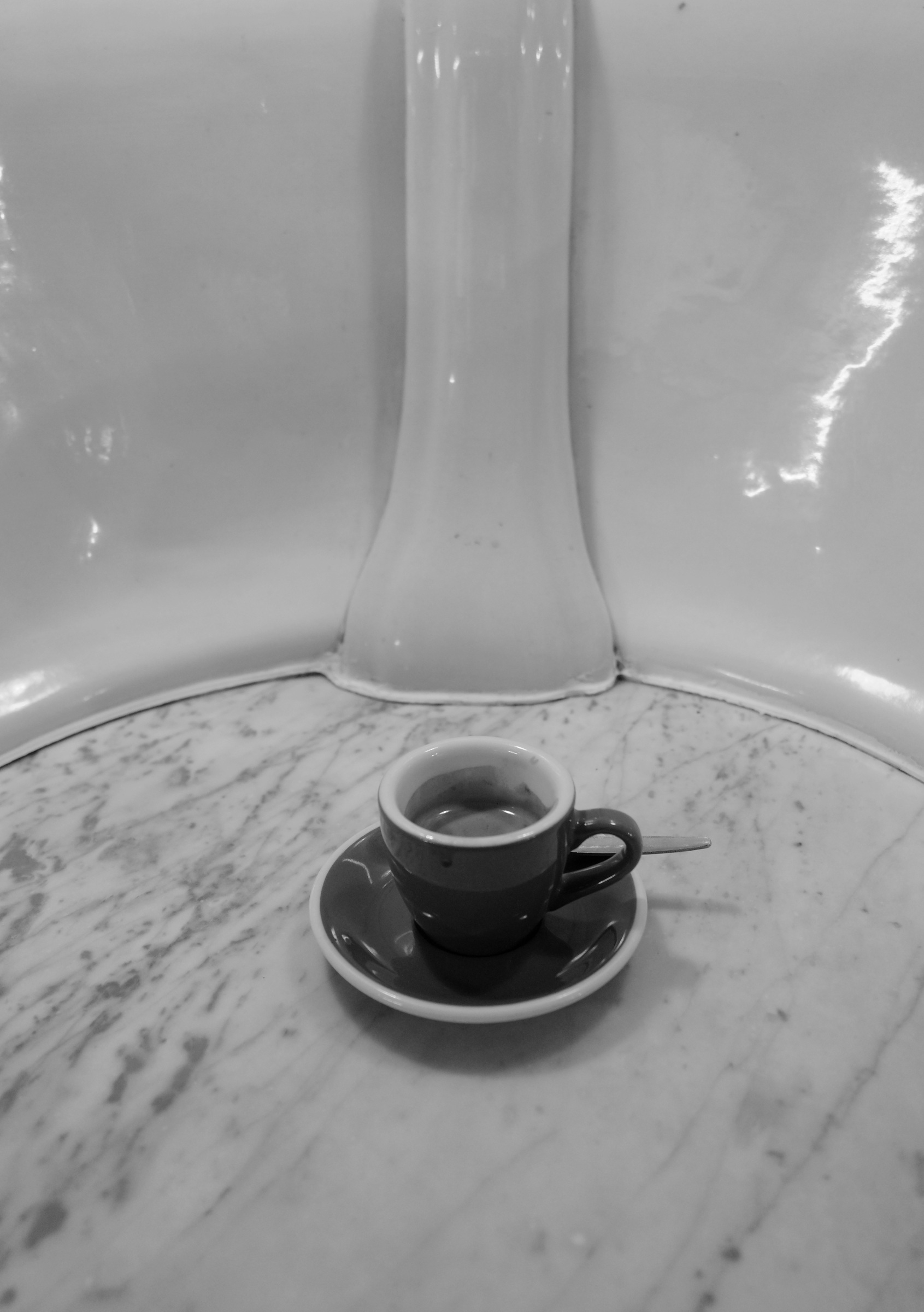 An espresso cup sits on a round marble counter beneath curved ceramic walls.