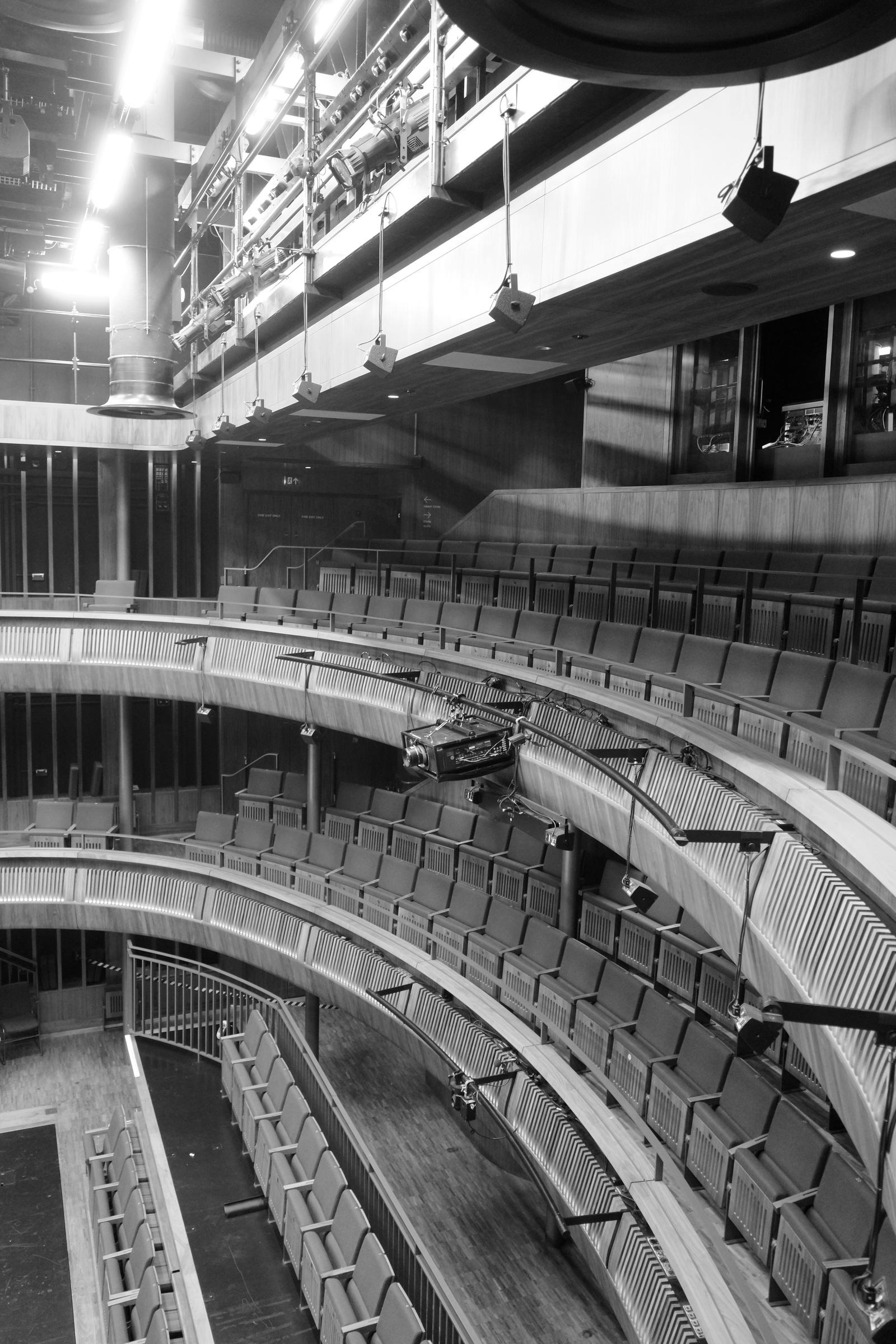 Empty theater seats curve beneath suspended stage equipment.